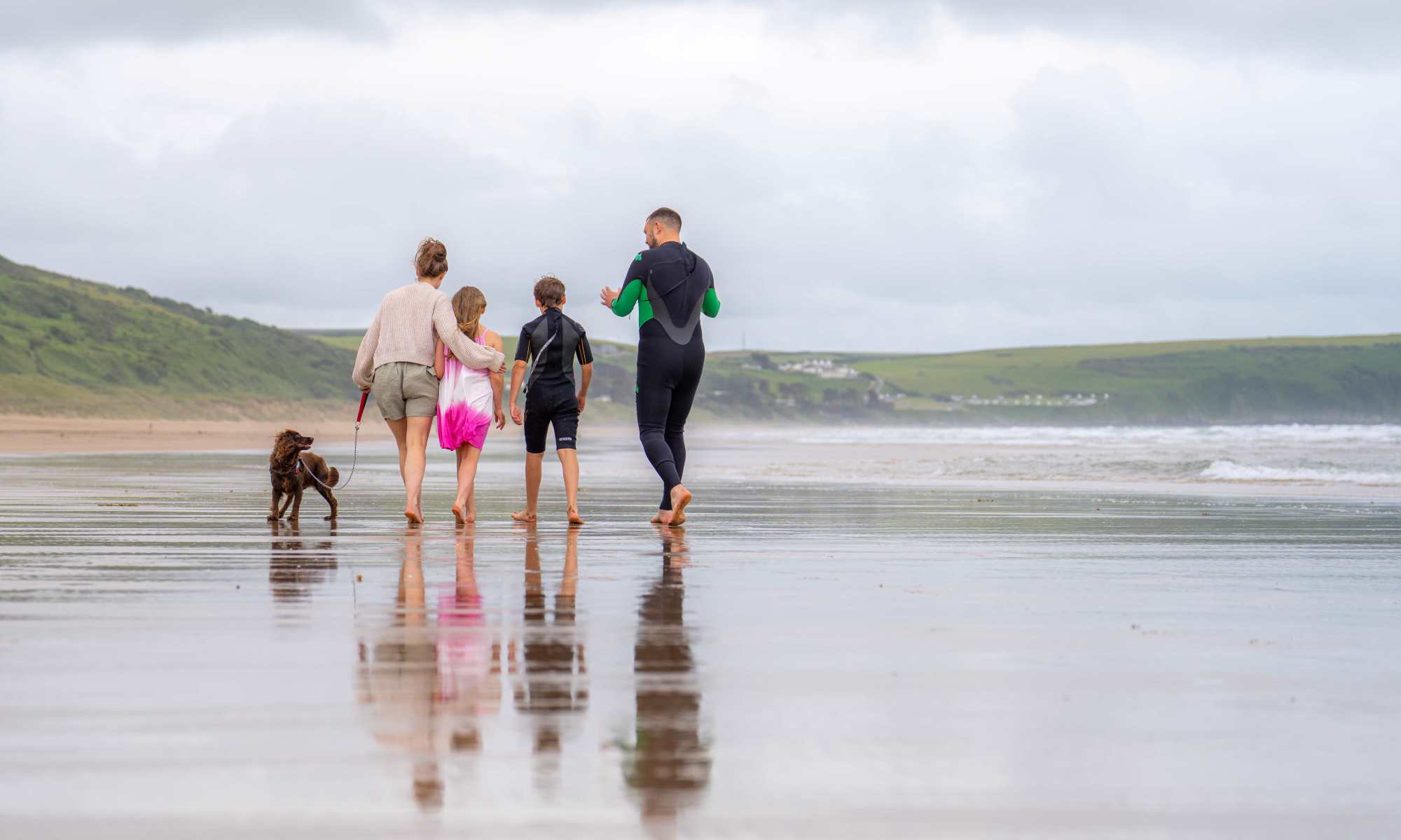 A family walking their dog on Woolacombe beach