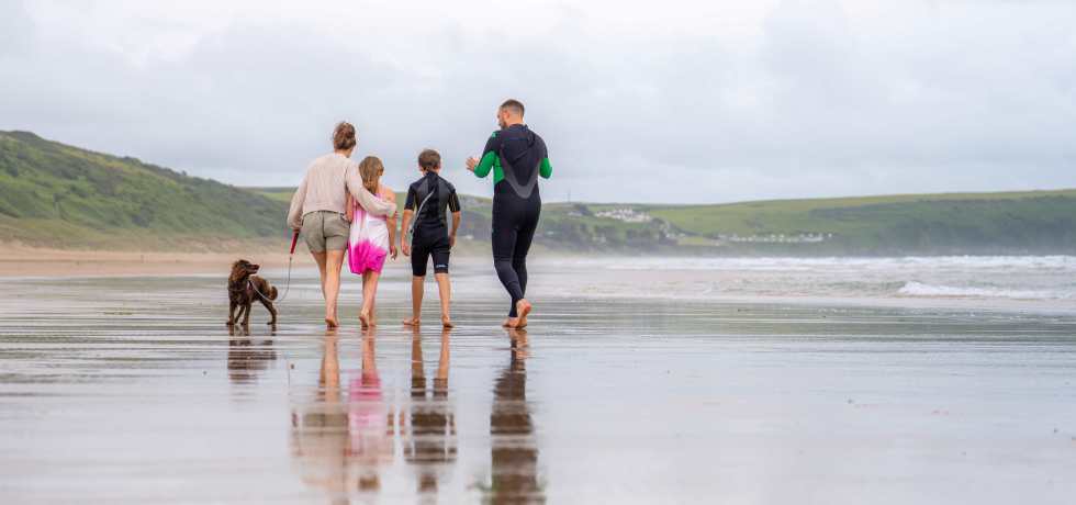 A family walking their dog on Woolacombe beach